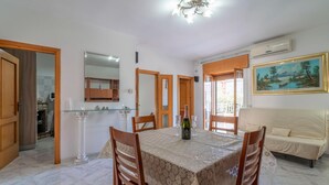 A dining area with a table set for two, a sofa, and a painting on the wall. - Pet friendly apartment in Carovigno (Carovigno)