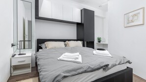 Un dormitorio moderno con una cama, mesitas de noche, un espejo y una planta pequeña.