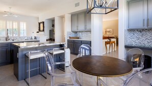 A modern kitchen with a central island, bar stools, and a dining table. - Luxury, spacious, spa home, sleeps 8, Chef Kitchen, office, and separate casita. (Palm Desert)