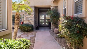 A residential building with a stone facade, a front door, a pathway, and a dog in the driveway. - Luxury, spacious, spa home, sleeps 8, Chef Kitchen, office, and separate casita. (Palm Desert)