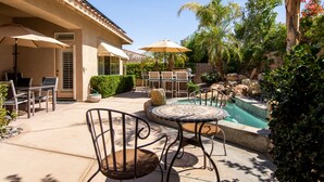 A patio with outdoor furniture, a swimming pool, and surrounding greenery. - Luxury, spacious, spa home, sleeps 8, Chef Kitchen, office, and separate casita. (Palm Desert)