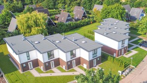 Un complesso residenziale moderno con diverse case a due piani, ognuna con tetto piatto e pareti esterne in bianco e marrone.