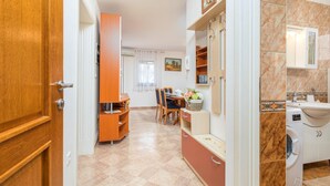 A hotel room with a wooden wardrobe, a dining area with a table and chairs, a kitchen area with a washing machine, and a bathroom with a sink and mirror. - Beautiful apartment in Fazana with WiFi (Fazana)