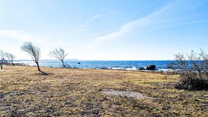 Rannikkomaisema, jossa on niukasti kasvillisuutta ja kirkas taivas.