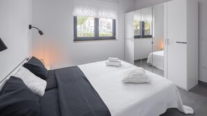 A modern bedroom with a bed, bedside tables, a wardrobe, and a window with a view of buildings. - Pet friendly home in Novigrad (Novigrad)