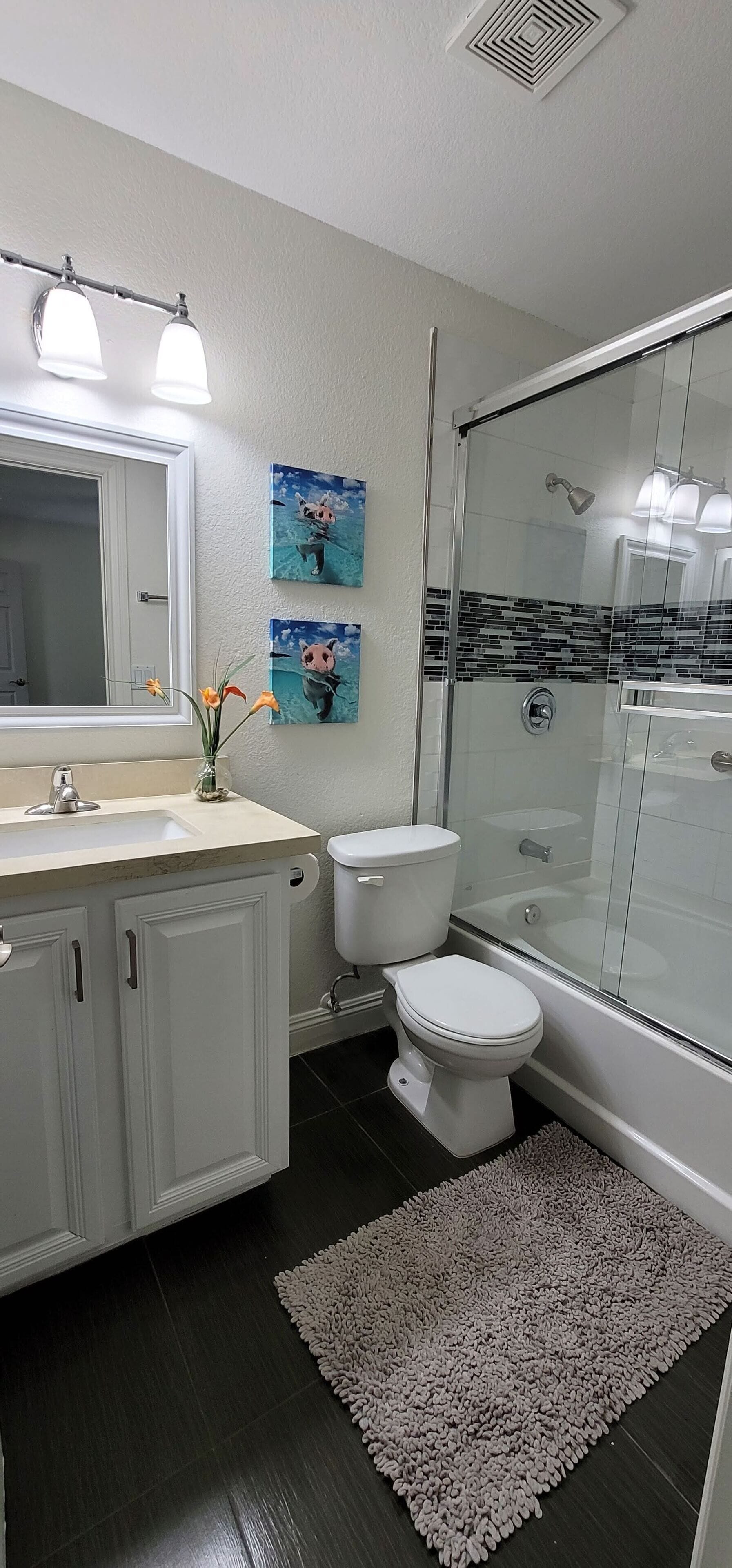 A modern bathroom with a glass shower enclosure, a white toilet, and a vanity with a mirror.