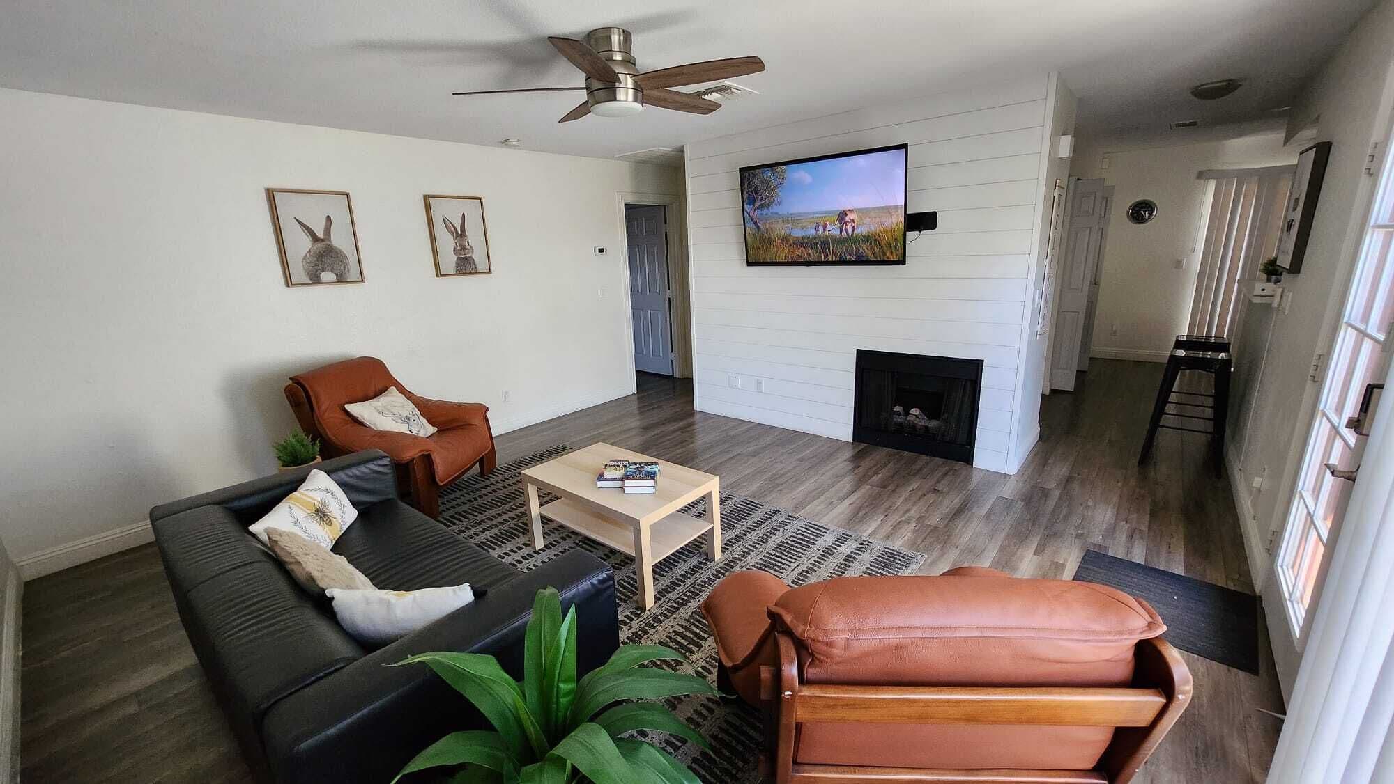 A living room with a black leather sofa, a brown leather armchair, a wooden coffee table, and a fireplace.