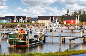 Boats dock at the marina, surrounded by calm water and scenic buildings.