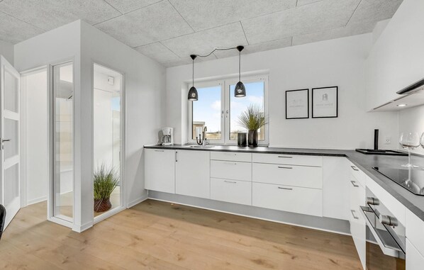 A modern kitchen with white cabinetry, a wooden floor, and pendant lighting. - Awesome apartment in Ringkøbing (Ringkøbing)