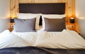 A bed with white bedding and two pillows, a dark headboard, and two wall-mounted lamps. - 1 bedroom nice home in Untergriesbach (Untergriesbach)