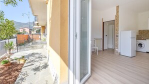 A balcony with a view of a street and buildings, a sliding glass door leading to a room with a washing machine and a refrigerator. - Cozy apartment in Rapallo with WiFi (Rapallo)