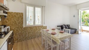 A compact kitchen with a dining area, a sofa, and a view of greenery outside. - Cozy apartment in Rapallo with WiFi (Rapallo)