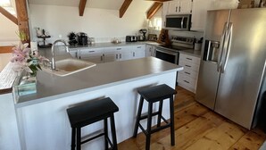 A modern kitchen with white cabinets, stainless steel appliances, and a wooden ceiling. - 4 Bedroom, Upside Down Post and Beam Nantucket Home (Nantucket)