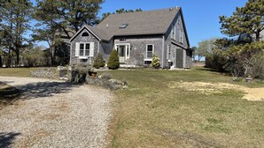 A two-story house with a gabled roof, a front porch, and a gravel driveway. - 4 Bedroom, Upside Down Post and Beam Nantucket Home (Nantucket)