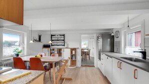 A modern kitchen with white cabinets, a dining area with a table and chairs, and a view of the outside through a window. - Lovely home in Thisted with kitchen (Thisted)