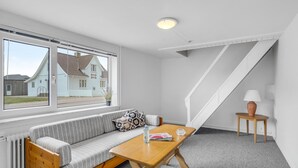 A modern, well-lit room with a large window, a wooden bench, a sofa, a small table, and a lamp. - Lovely home in Thisted with kitchen (Thisted)