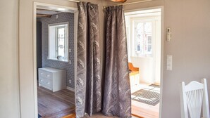 Ein Zimmer mit Holzboden, einem weißen Stuhl und einem Fenster mit Blick ins Freie.