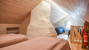Ein gemütliches Schlafzimmer im Dachgeschoss mit zwei Betten, einer Holzbalkendecke und einem Feuerlöscher.