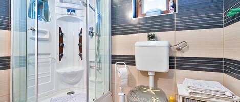 A modern bathroom with a glass-enclosed shower, a toilet, and a sink.