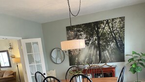 A dining area with a wooden table and black chairs, a patterned rug, and a large painting on the wall. - World Track Championships-3 Bedroom Home. Car available. (Eugene)