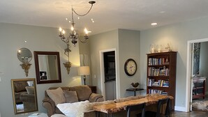 A spacious living room with a large wooden dining table, a beige sofa, and a bookshelf. - World Track Championships-3 Bedroom Home. Car available. (Eugene)