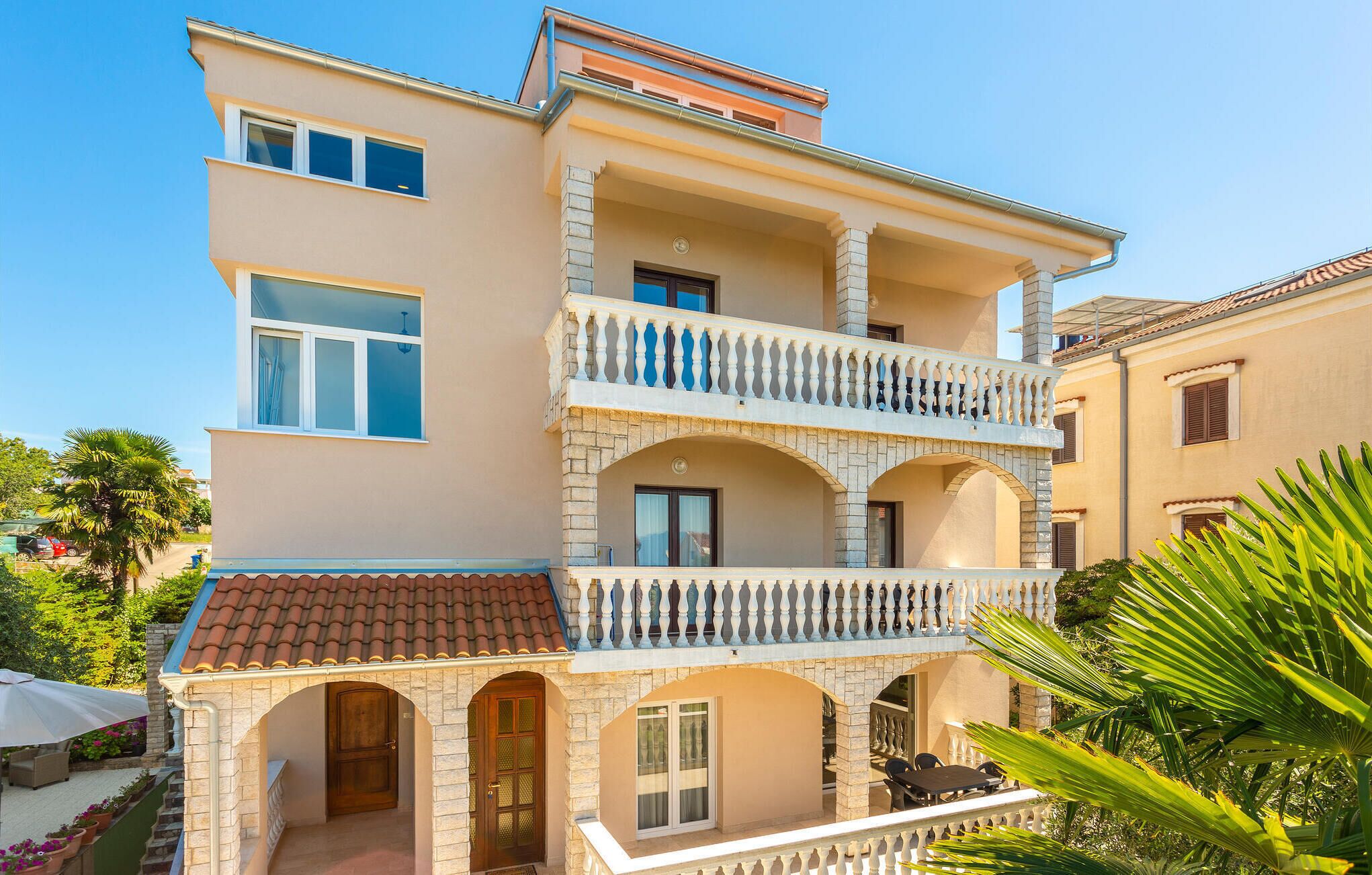 Ein mehrstöckiges Gebäude mit Balkon, Steinbögen und einem Ziegeldach.
