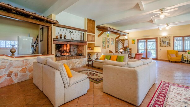 A spacious living room with a fireplace, two sofas, a dining table, and a kitchen area with a refrigerator. - Gorgeous home in Montalto di Castro (Montalto di Castro)