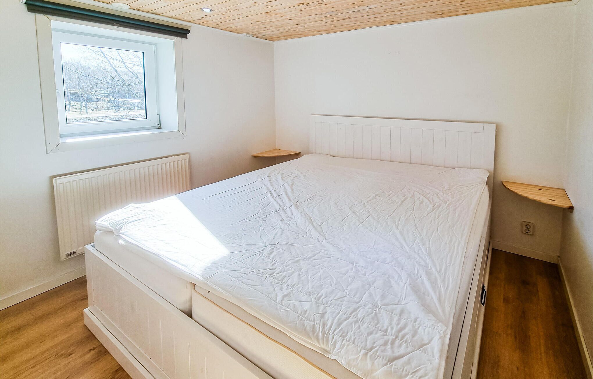 Une chambre à coucher avec un lit, une fenêtre, un radiateur et un plancher en bois.