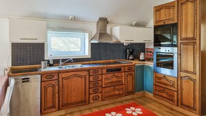 A kitchen with wooden cabinets, a built-in oven, and a window above the sink.