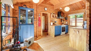 Une cabane en bois dotée d’un coin cuisine comprenant un meuble bleu, une cuisinière et un évier.