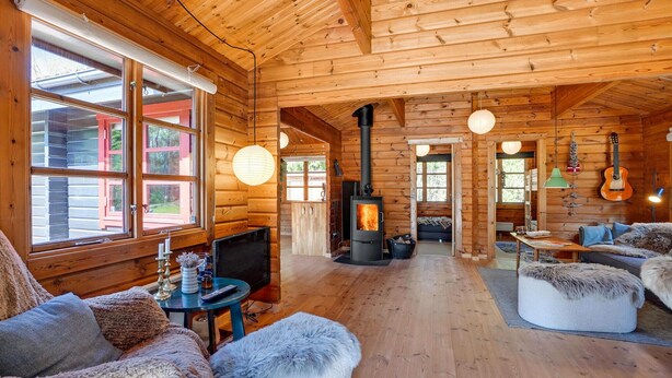 L’intérieur chaleureux d’un chalet en bois, avec une cheminée, des murs en bois et un coin salon confortable.