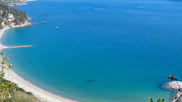 A coastal view with a clear blue sea, a sandy beach, and a rocky outcrop with a flag. - 2 bedroom beach front apartment in Andora (Andora)