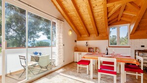 A dining area with a wooden ceiling, a large window, and a table set for four. - 2 bedroom beach front apartment in Andora (Andora)
