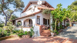 A two-story house with a patio, a chimney, and a garden with various plants and trees. - 2 bedroom beach front apartment in Andora (Andora)
