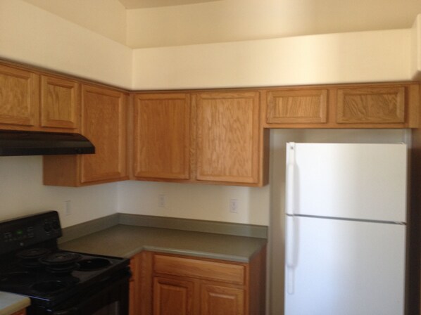 A kitchen with wooden cabinets, a black stove, and a white refrigerator. - Birdwatchers Paradise on 1.5 ac Golfing hiking & More (Rio Rico)