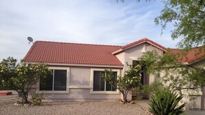 Une maison avec un toit recouvert de tuiles rouges, deux fenêtres et une allée gravillonnée.