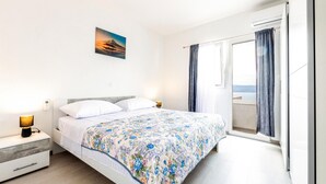 Een moderne hotelkamer met een groot bed, een nachtkastje met een lamp, een wandairconditioner en een raam met gordijnen.