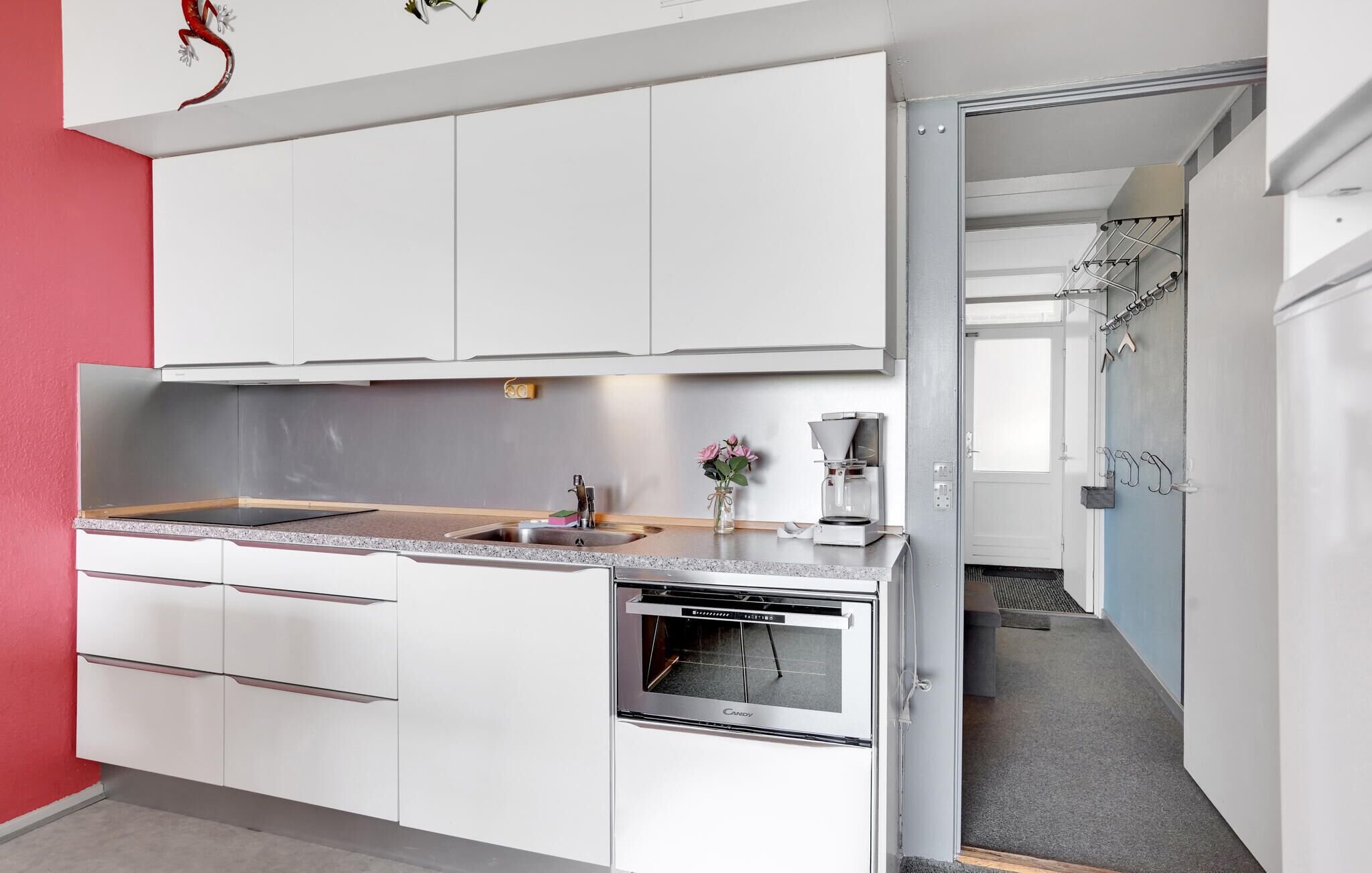 Eine moderne Küche mit weißen Schränken, einer Granitabdeckung, einem eingebauten Backofen und einer Kaffeemaschine.