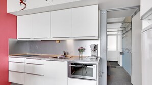 Una cocina moderna con gabinetes blancos, encimera de granito, horno empotrado y cafetera.