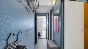 Un pasillo con pared azul, un banco y una puerta que da a un baño con cortina de ducha a rayas rosadas y blancas.