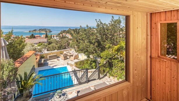 Un balcon en bois offrant une vue sur une piscine, une petite île et les bâtiments environnants.