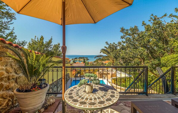Enjoy the ocean view from this balcony with a round table and potted plant.