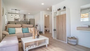A modern living room with a sofa, a coffee table, and a kitchen in the background. - Amazing home in Arenas (Arenas)