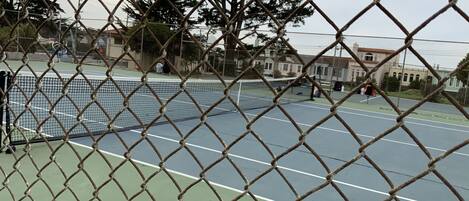 A chain-link fence surrounding a tennis court with a net.