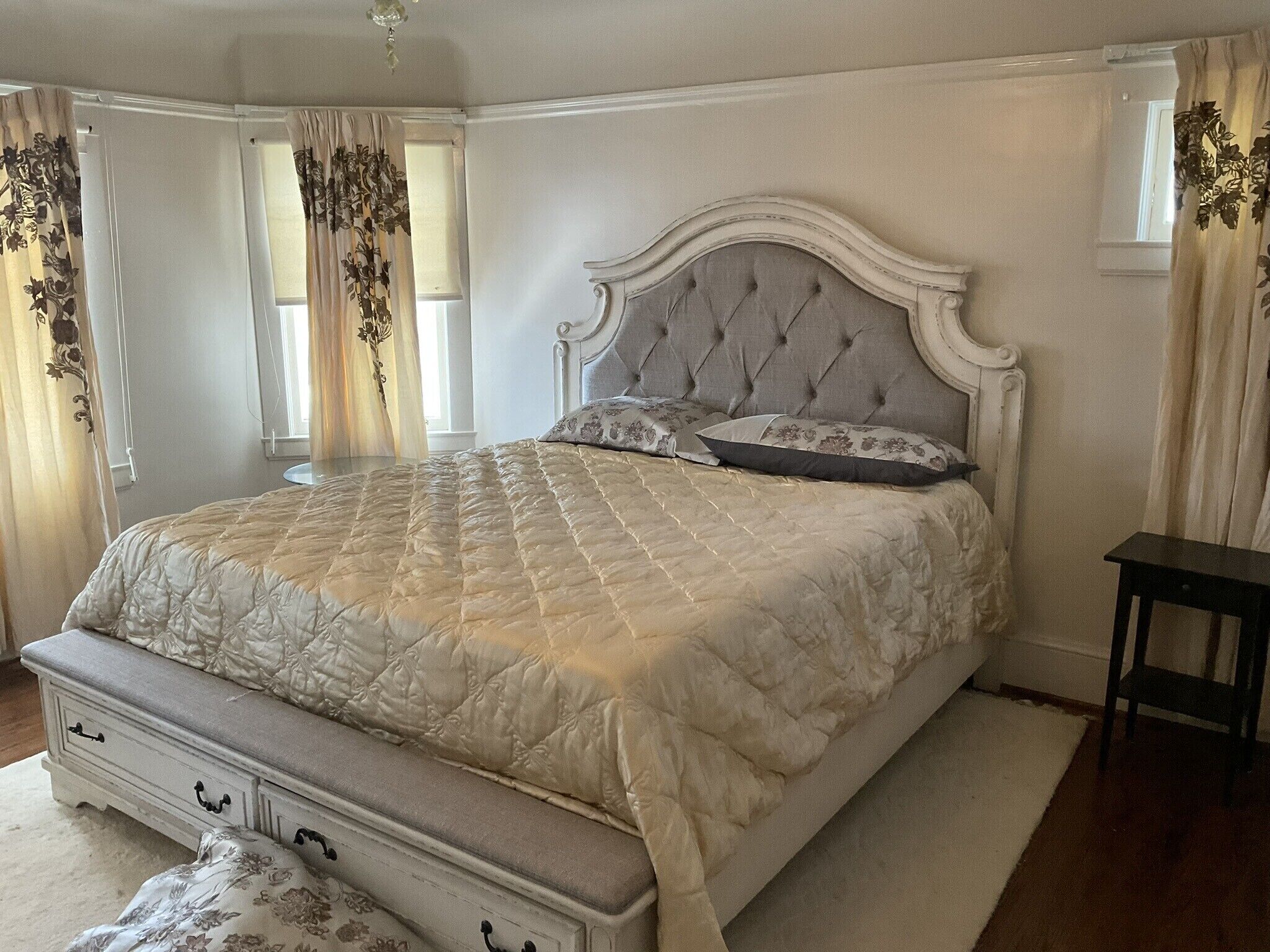 A bedroom with a large bed, a dresser with drawers, and a small table.