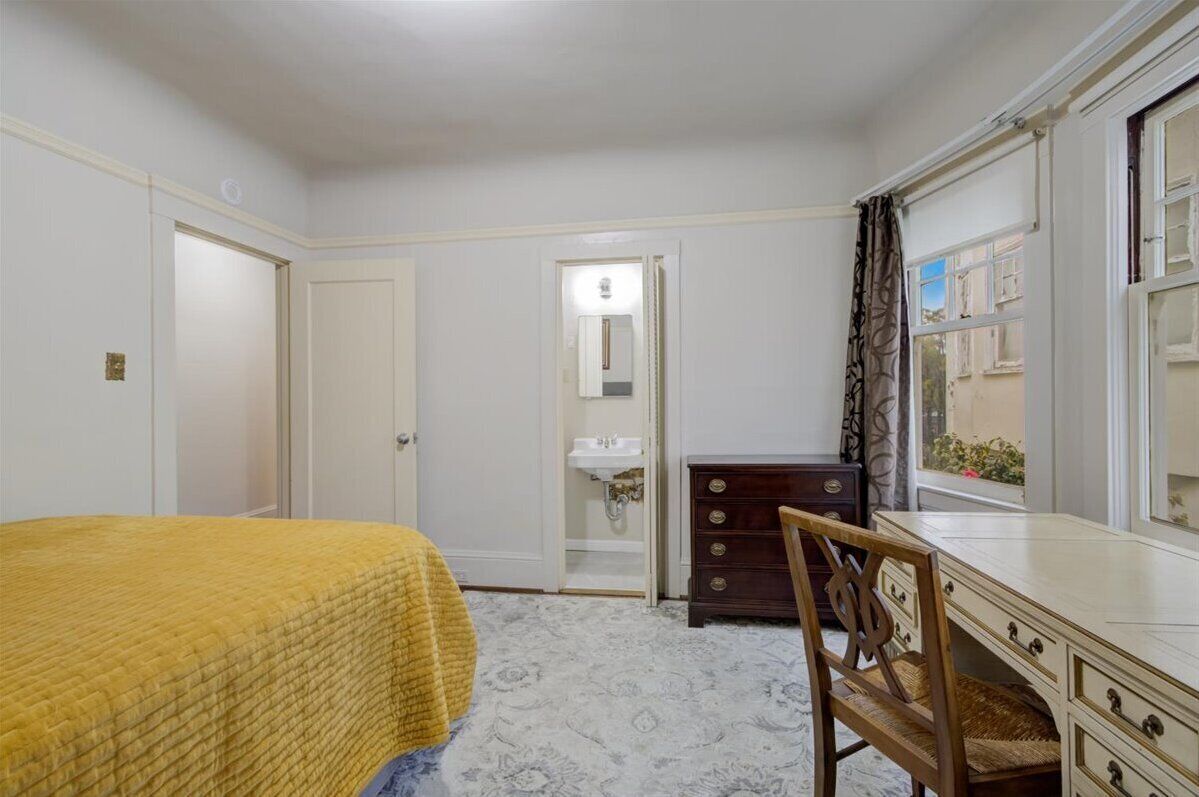 A bedroom with a bed, a dresser, a chair, and a window with curtains.
