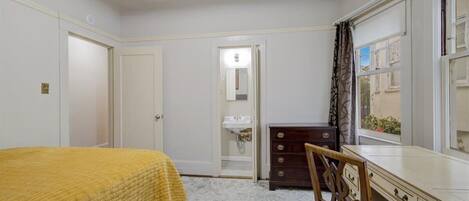 A bedroom with a bed, a dresser, a chair, and a window with curtains.