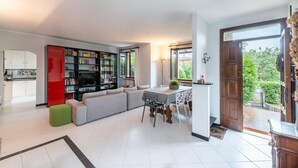 Una sala moderna con sofá, una mesa de comedor y una cocina visible a través de un arco.