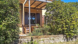 Un edificio rústico con un balcón de madera, una pared de piedra y abundante vegetación.