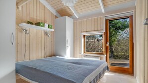 Ein Schlafzimmer mit einem Bett, einem Fenster und einer Tür, die zu einem Außenbereich führt.